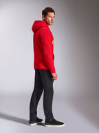 Alpinestars Ride V3 Hoodie, abbigliamento sportivo casual, rosso con marchio giallo alta visibilità, modello che indossa la felpa rossa con pantaloni neri e sneaker, vista di profilo, design pullover in pile con polsini e orlo a coste.