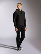 Alpinestars Sessions V3 Hoodie, felpa in pile di poliestere con zip frontale, nera e grigia, loghi grigi su petto e maniche, cappuccio con coulisse e punte dei cordini rosse, vista a figura intera del modello in abbigliamento casual motorsport streetwear