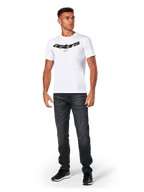 Alpinestars Elliptic CSF Tee, maglietta a maniche corte, bianca, logo Astars arcuato nero con simbolo della stella arancione, indossata da un modello con jeans neri e sneakers, streetwear casual motorsport