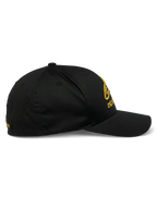 Cappello Alpinestars Gild, berretto sportswear, nero e oro, vista laterale con visiera curva, corona strutturata e ricamo 3D metallico dorato sul davanti e di lato, tessuto twill elasticizzato