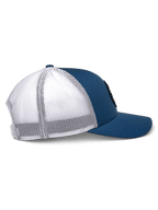 Cappello Trucker Alpinestars Gambit, blu e bianco, vista di profilo laterale, visiera curva con corona strutturata, pannelli frontali in twill blu e retro in rete di poliestere bianca, copricapo casual ispirato al motorsport