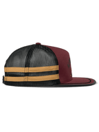 Cappello Trucker Alpinestars Backline, nei colori mattone, nero e senape, vista laterale di profilo, parte anteriore in twill rosso scuro con retro in rete nera e strisce laterali gialle, visiera piatta con bordo in suttache nero, copricapo casual ispirato al motorsport