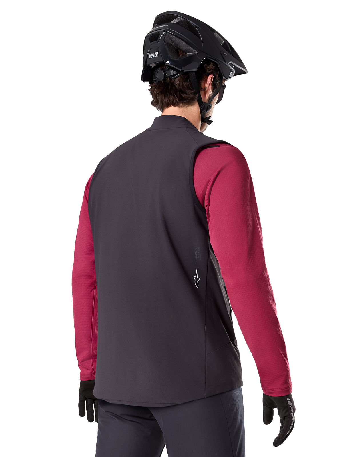 Gilet Termico Alpinestars A-Dura, nero, vista posteriore, indossato sopra una maglia a maniche lunghe bordeaux con casco da mountain bike e guanti neri, abbigliamento da ciclismo isolante leggero per il fuoristrada