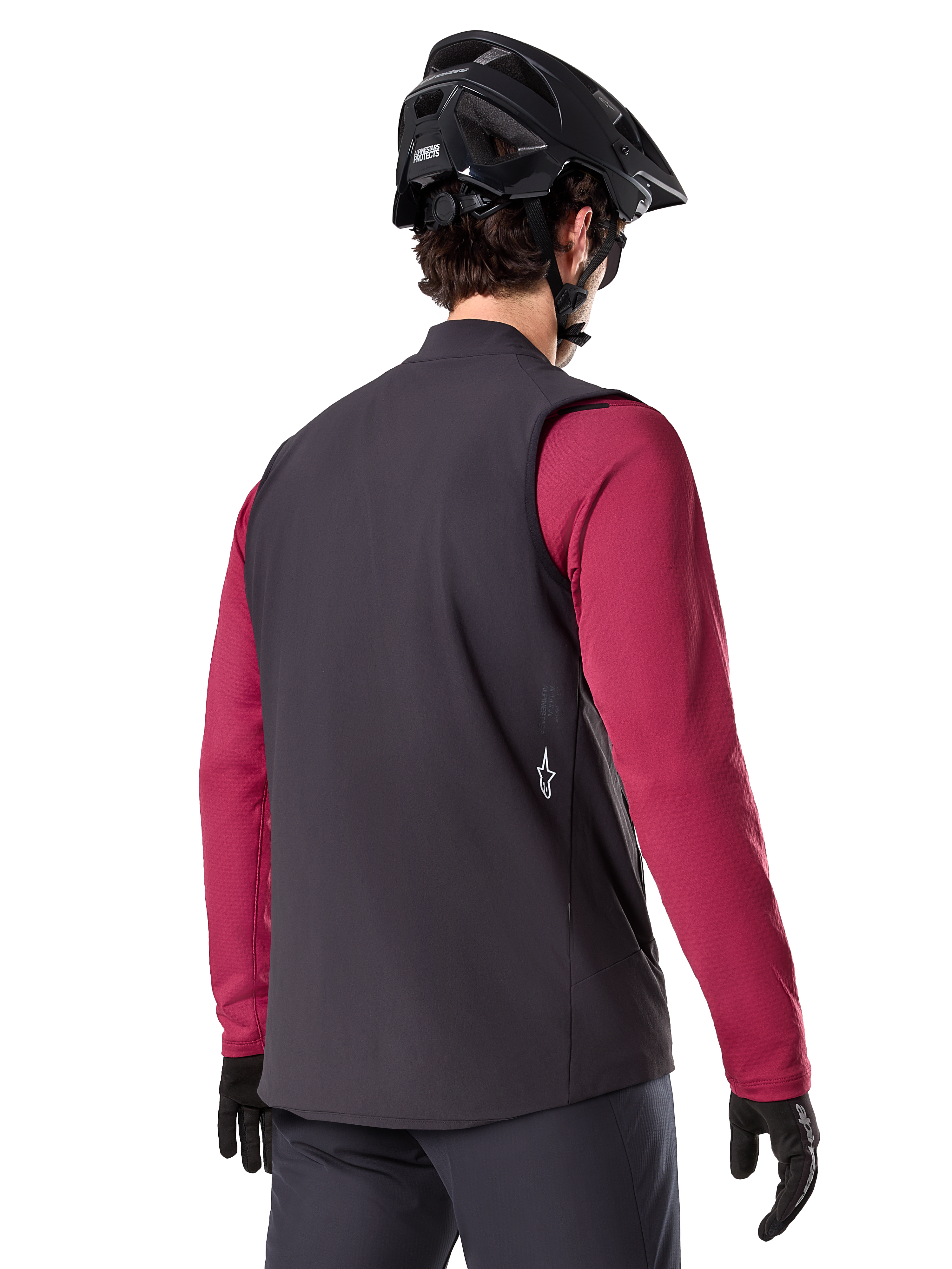 Gilet Termico Alpinestars A-Dura, nero, vista posteriore, indossato sopra una maglia a maniche lunghe bordeaux con casco da mountain bike e guanti neri, abbigliamento da ciclismo isolante leggero per il fuoristrada