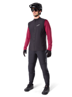 Gilet Termico Alpinestars A-Dura, gilet da ciclismo nero, indossato da un rider sopra una maglia a maniche lunghe bordeaux e pantaloni neri, con casco da MTB e guanti neri, progettato per il mountain biking in climi freddi