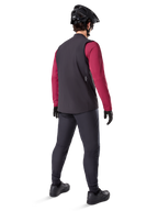 Alpinestars Gilet Termico A-Dura, gilet da ciclismo nero, mostrato dal retro su un modello che indossa una maglia a maniche lunghe bordeaux e pantaloni da ciclismo neri, abbinato a casco e guanti da mountain bike neri, abbigliamento tecnico per il freddo
