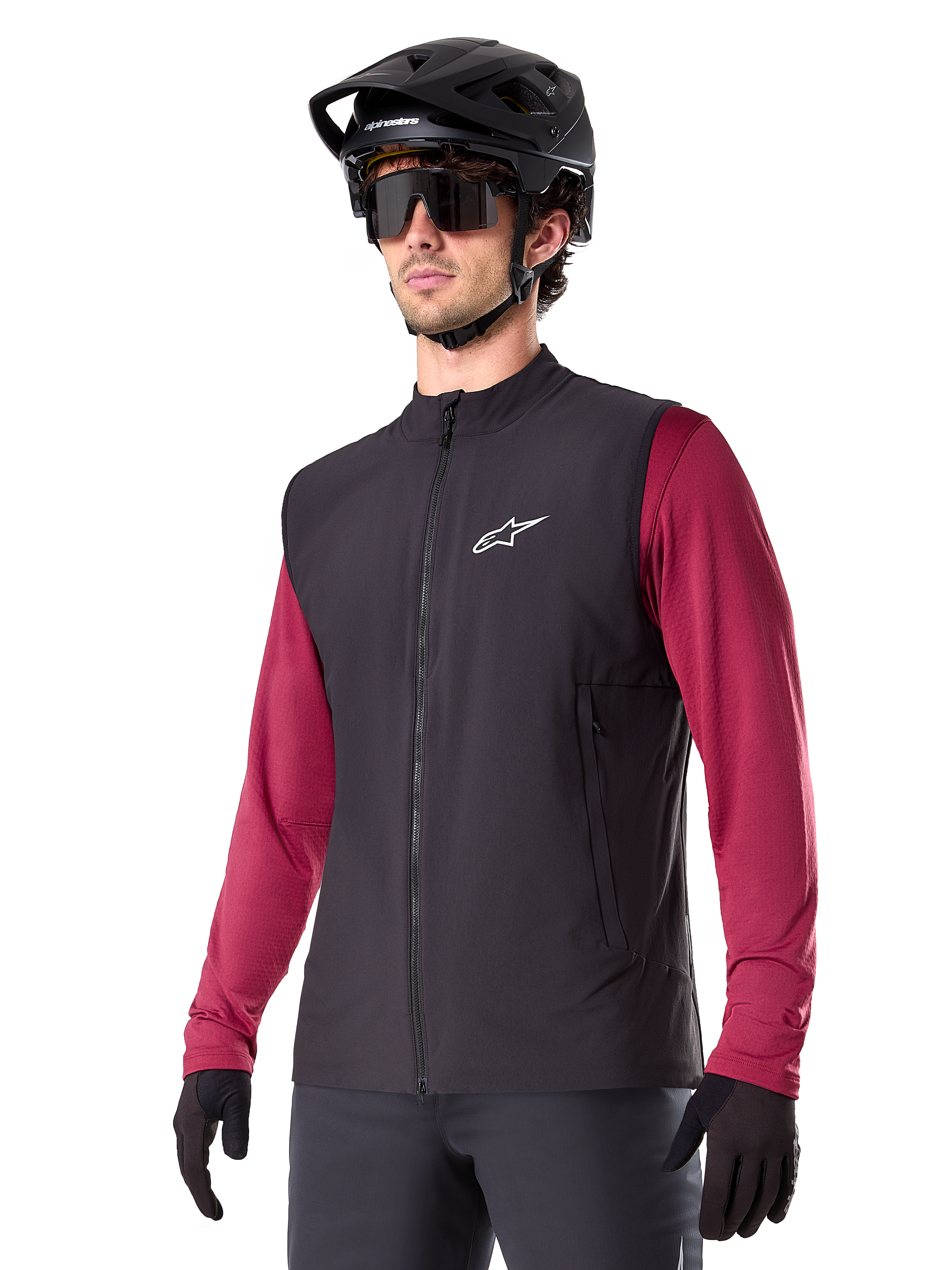 Alpinestars A-Dura Thermal Vest, gilet termico nero da ciclismo, indossato sopra una maglia bordeaux a maniche lunghe, con logo bianco sul petto, abbinato a un casco da MTB nero e occhiali da sole, strato isolante performante per mountain bike