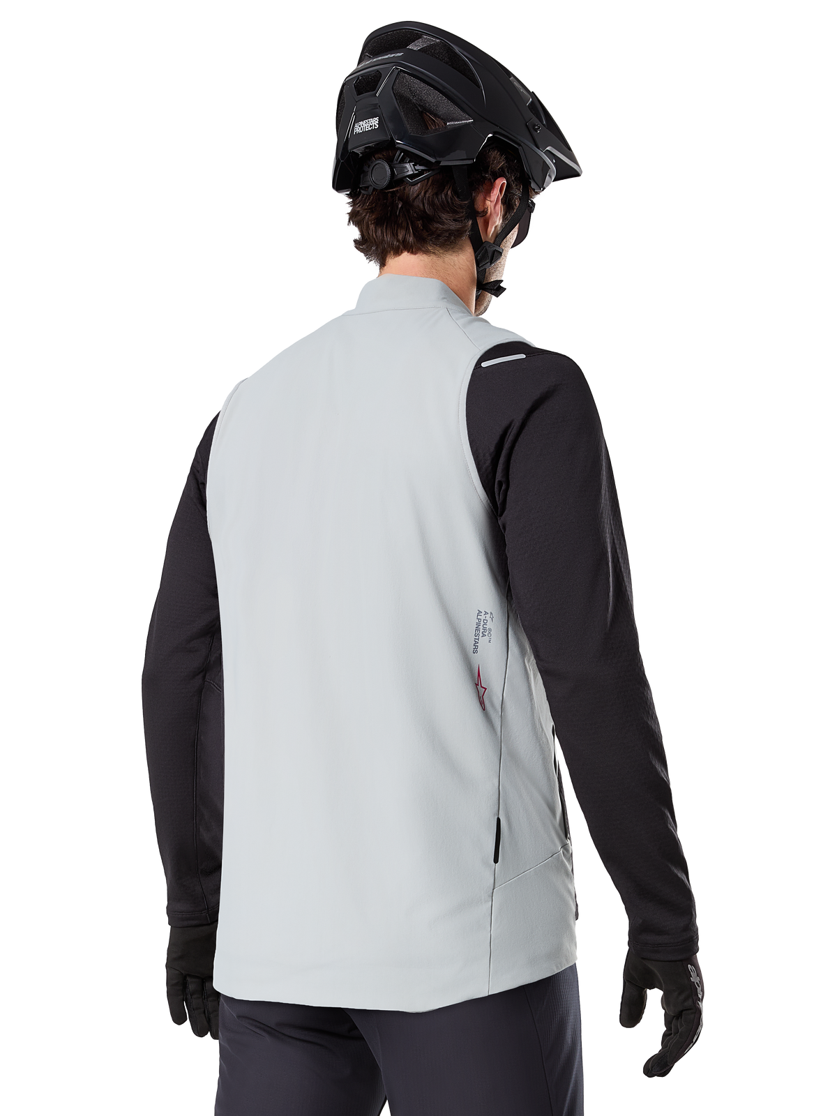 Alpinestars A-Dura Thermal Vest, Grigio Titanium, vista posteriore di un modello che indossa una maglia nera a maniche lunghe e un casco da MTB, design minimalista con un piccolo logo a stella rosso sul retro, gilet da ciclismo leggero e isolato per il fuoristrada