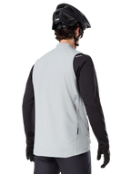 Alpinestars A-Dura Thermal Vest, Grigio Titanium, vista posteriore di un modello che indossa una maglia nera a maniche lunghe e un casco da MTB, design minimalista con un piccolo logo a stella rosso sul retro, gilet da ciclismo leggero e isolato per il fuoristrada