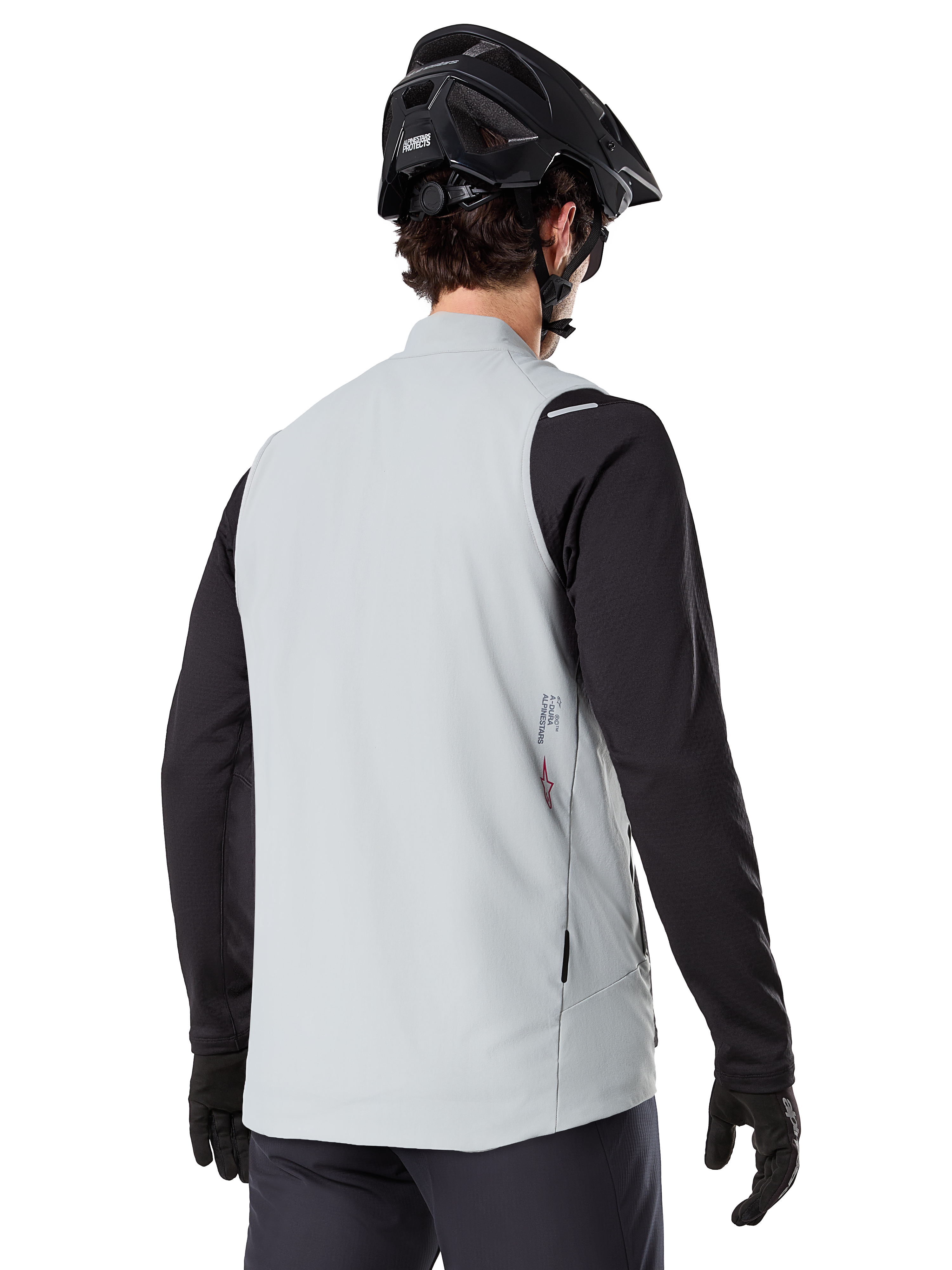 Alpinestars A-Dura Thermal Vest, Grigio Titanium, vista posteriore di un modello che indossa una maglia nera a maniche lunghe e un casco da MTB, design minimalista con un piccolo logo a stella rosso sul retro, gilet da ciclismo leggero e isolato per il fuoristrada