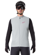Gilet termico Alpinestars A-Dura, gilet da ciclismo, grigio titanio, indossato con una maglia a maniche lunghe nera e un casco da ciclismo nero, logo a stella Alpinestars rosso sul petto, leggero e isolato per la mountain bike.