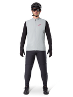 Alpinestars A-Dura Thermal Vest, gilet da ciclismo, grigio titanio, indossato con maglia a maniche lunghe nera e pantaloni neri, casco nero e occhiali da sole, con logo Alpinestars rosso, isolamento termico leggero per mountain bike