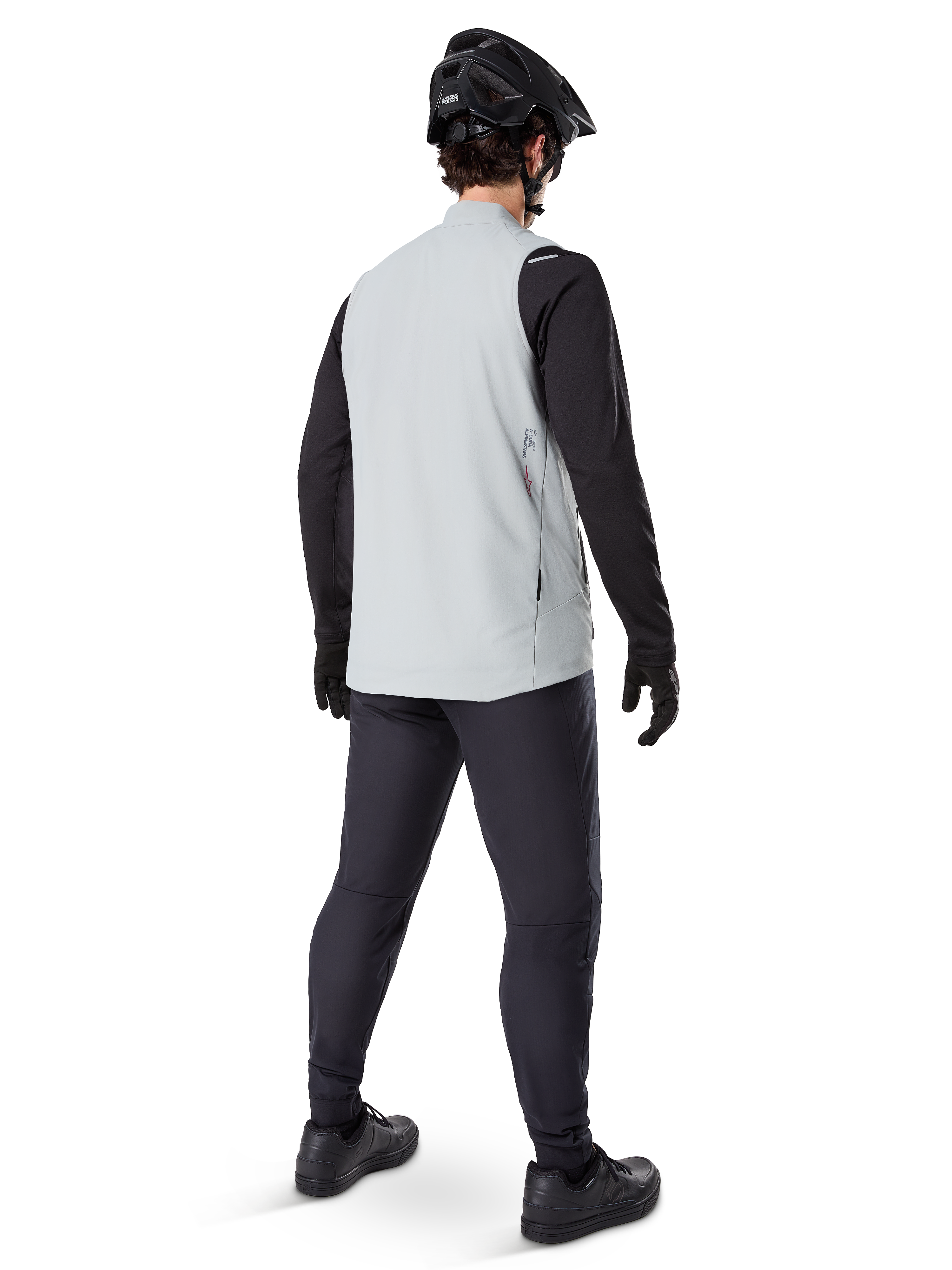 Alpinestars A-Dura Thermal Vest, grigio titanio, vista posteriore del modello che indossa il gilet da ciclismo isolato sopra una maglia nera a maniche lunghe e pantaloni scuri, completo di casco da mountain bike e guanti neri, progettato per la guida fuoristrada in condizioni fredde