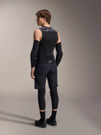 Modello maschile visto di spalle che indossa il gilet protettivo Alpinestars A-Motion Plasma, Black Camo, design in mesh senza maniche con paraschiena integrato, motivo mimetico grigio sulle spalle, abbinato a gomitiere nere e pantaloncini da mountain bike, abbigliamento tecnico da ciclismo