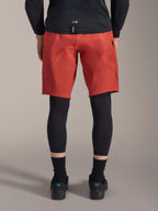 Alpinestars A-Motion Plasma Knee Sleeve, protezioni per ginocchia da MTB nere, vista posteriore indossate sotto pantaloncini rossi da mountain bike con maglia nera e scarpe tecniche da ciclismo, attrezzatura protettiva per mountain bike