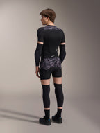 Modello che indossa i boxer protettivi Alpinestars A-Motion Plasma in Black Camo e la giacca protettiva A-Motion Plasma coordinata, vista posteriore con motivo mimetico grigio, gomitiere, ginocchiere e scarpe da ciclismo, set completo di protezioni per mountain bike