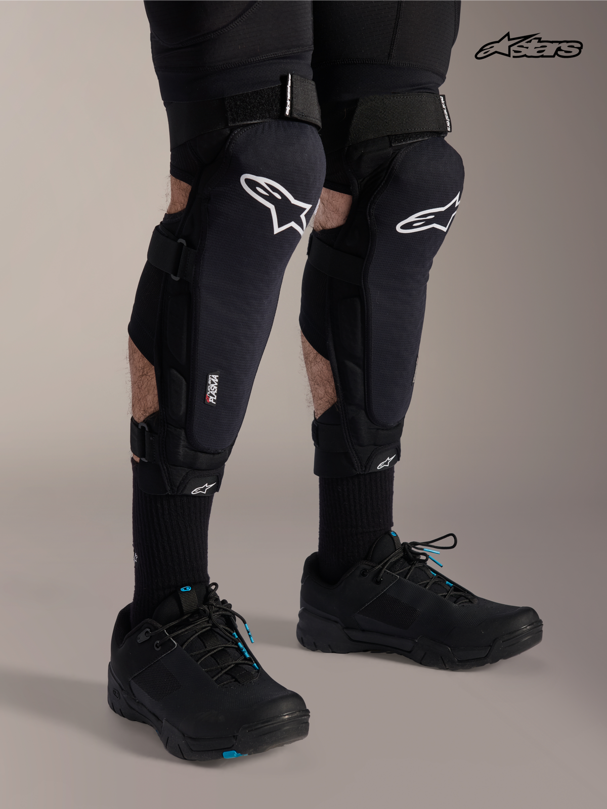 Alpinestars Protezione Ginocchio/Tibia A-Impact Plasma Pro, ginocchiere per mountain bike in nero con logo bianco, indossate da un modello che mostra il sistema di chiusura a triplo cinturino e la protezione Nucleon Plasma