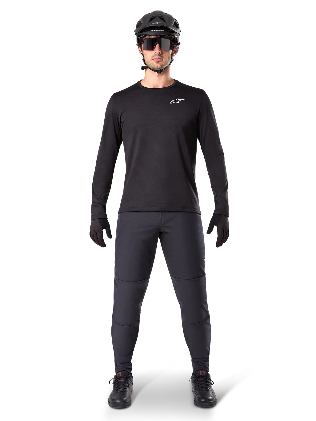 Alpinestars Pantaloni Termici A-Dura, nero, indossati da un rider con abbigliamento completo da mountain bike, maglia nera a maniche lunghe, casco e occhiali da sole, pantaloni resistenti con vestibilità regolare per trail riding in condizioni di freddo