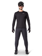 Alpinestars Pantaloni Termici A-Dura, nero, indossati da un rider con abbigliamento completo da mountain bike, maglia nera a maniche lunghe, casco e occhiali da sole, pantaloni resistenti con vestibilità regolare per trail riding in condizioni di freddo