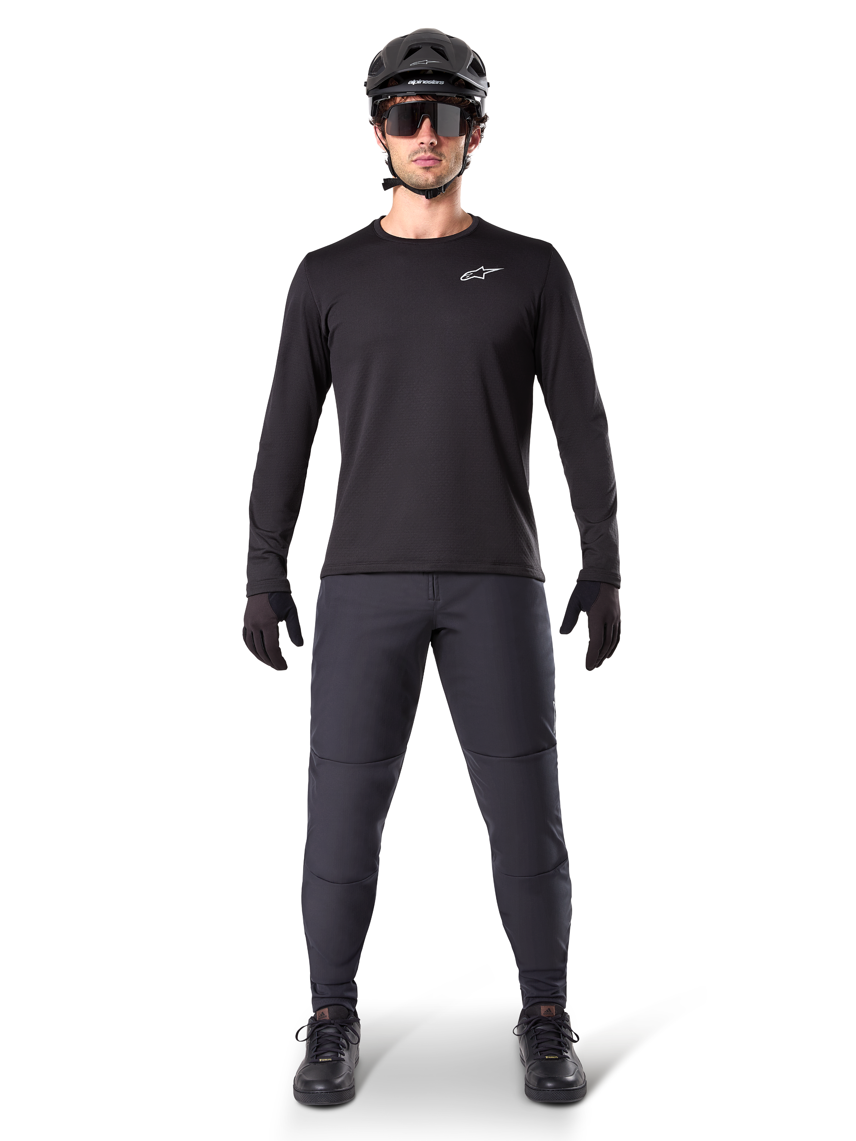 Alpinestars Pantaloni Termici A-Dura, nero, indossati da un rider con abbigliamento completo da mountain bike, maglia nera a maniche lunghe, casco e occhiali da sole, pantaloni resistenti con vestibilità regolare per trail riding in condizioni di freddo