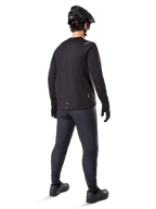 Alpinestars A-Dura Thermal Pant, pantaloni da mountain bike, nero, vista posteriore, indossati con maglia a maniche lunghe coordinata, casco da MTB nero e guanti, abbigliamento tecnico da ciclismo per climi freddi
