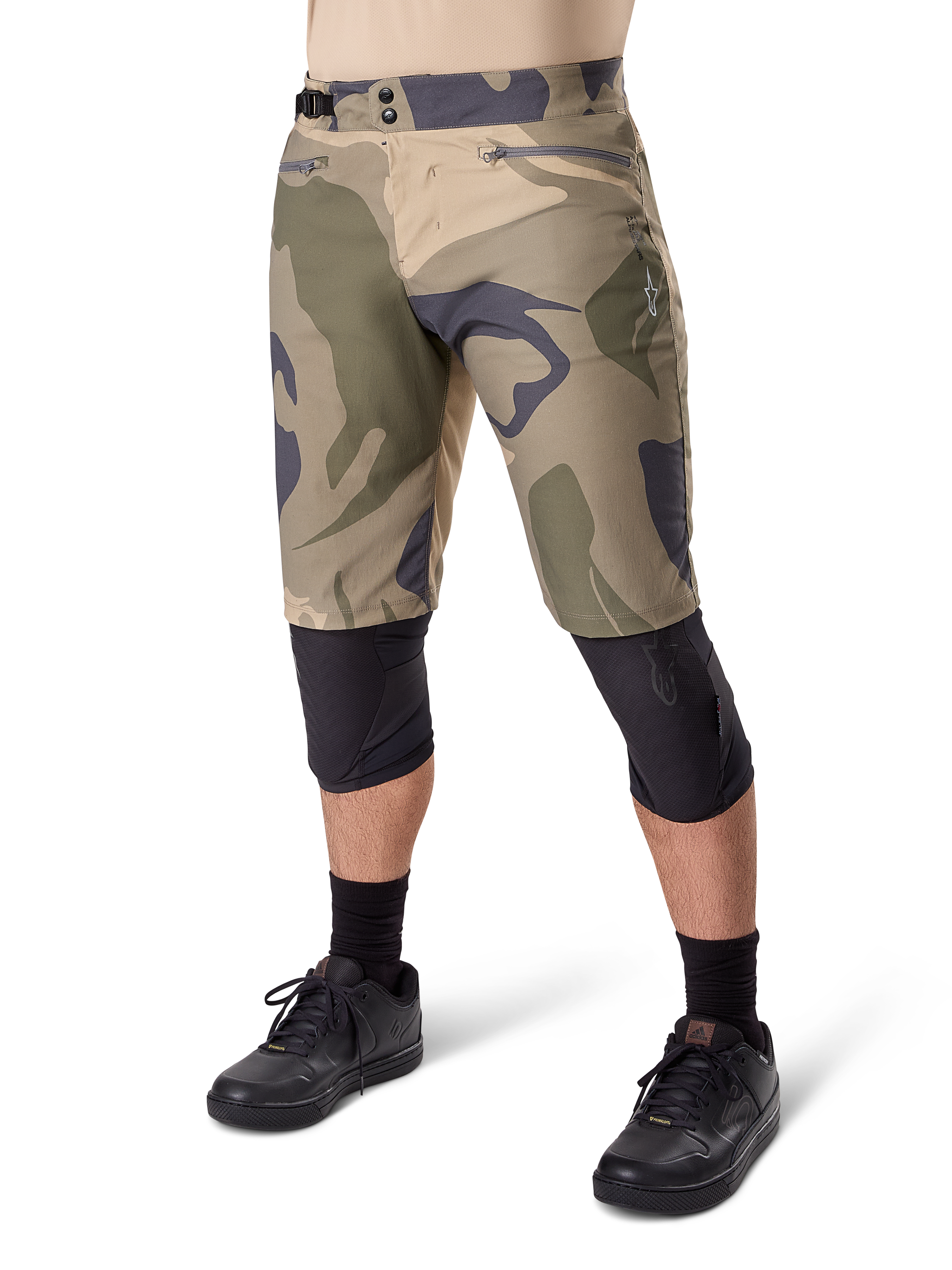 Alpinestars A-Dura Camo Liner Short, pantaloncini da mountain bike, fantasia mimetica marrone, vista frontale con tasche con zip e regolatori laterali in vita, indossati con ginocchiere nere e scarpe da ciclismo nere, attrezzatura resistente per MTB