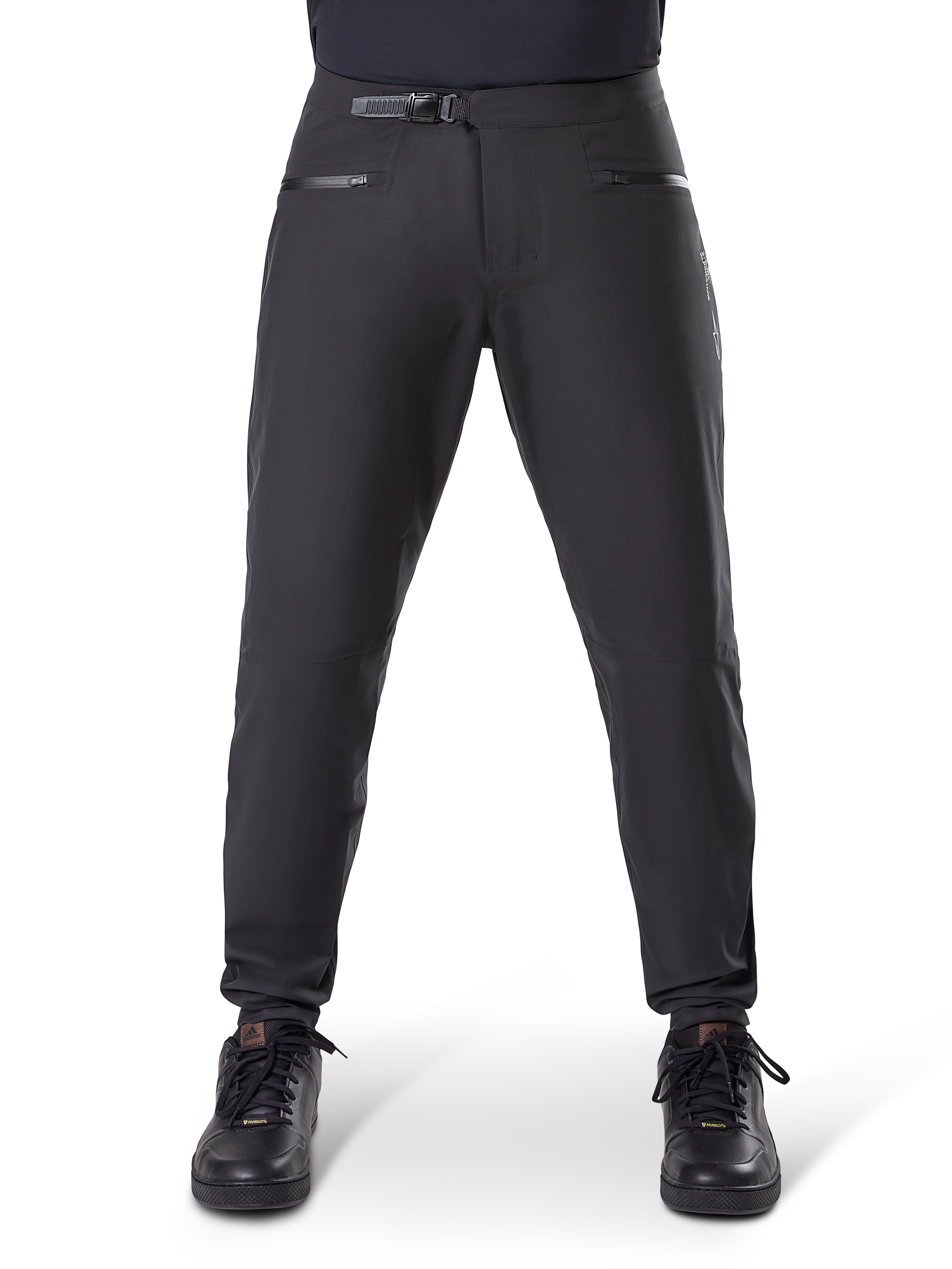 Pantaloni impermeabili Alpinestars A-Dura, nero, pantaloni da mountain bike con chiusura a cricchetto in vita e tasche con cerniera, vista frontale su modello abbinati a scarpe nere, abbigliamento impermeabile resistente per MTB