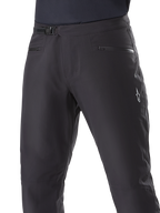 Pantaloni impermeabili Alpinestars A-Dura, pantaloni da mountain bike, nero, primo piano della vita con sistema di chiusura a cricchetto e tasche con cerniera, logo Alpinestars bianco sulla coscia, tessuto resistente per il trail riding in condizioni di bagnato