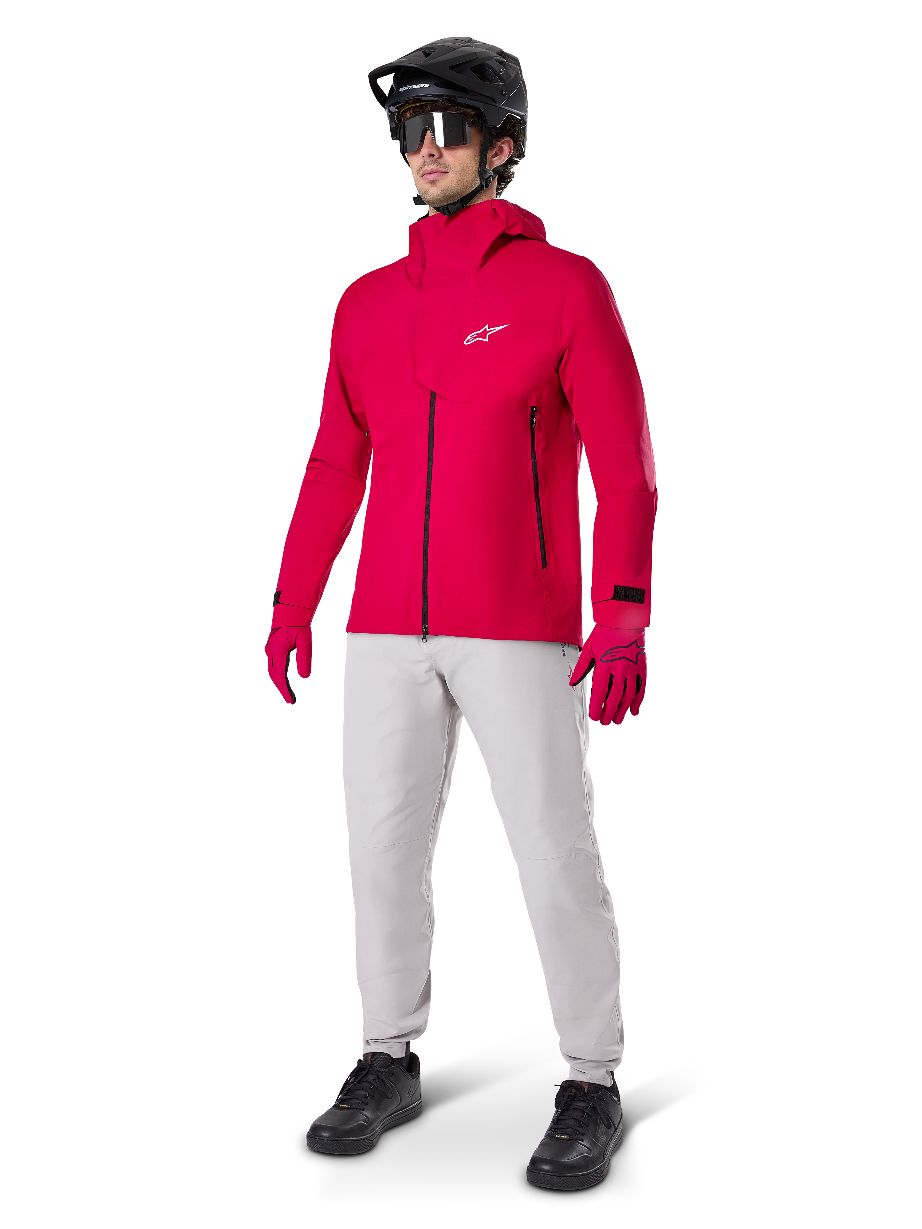 Modello che indossa i pantaloni impermeabili Alpinestars A-Dura in grigio Titanium, abbinati a una giacca impermeabile rosso acceso e guanti coordinati, casco da mountain bike nero con maschera e scarpe nere, abbigliamento completo da mountain bike per condizioni di sentieri bagnati