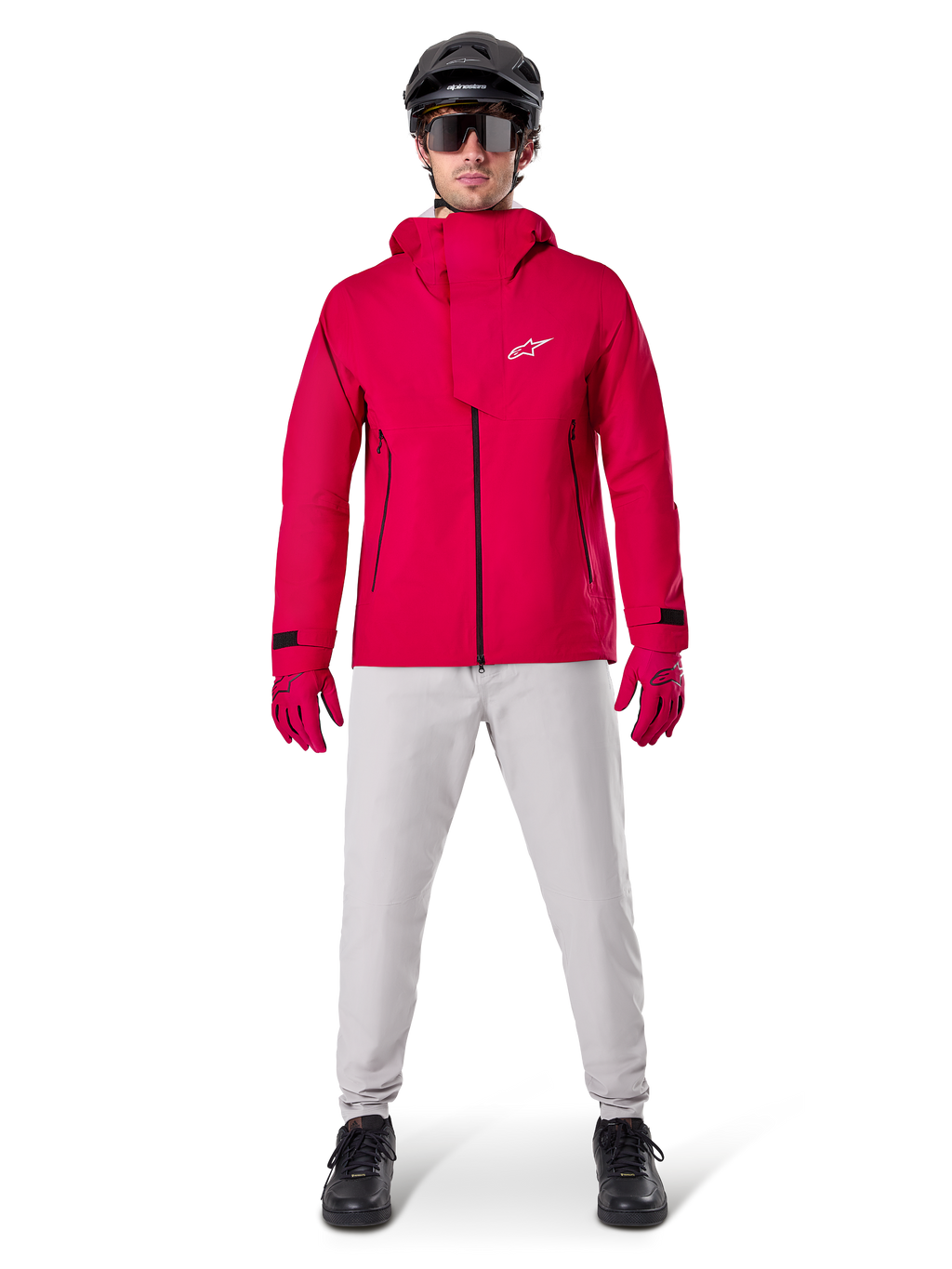 Pantaloni impermeabili Alpinestars A-Dura, pantaloni da MTB, grigio titanio, indossati con una giacca con cappuccio rosso vivace, guanti rossi e un casco da mountain bike nero, abbigliamento tecnico impermeabile professionale per percorsi bagnati