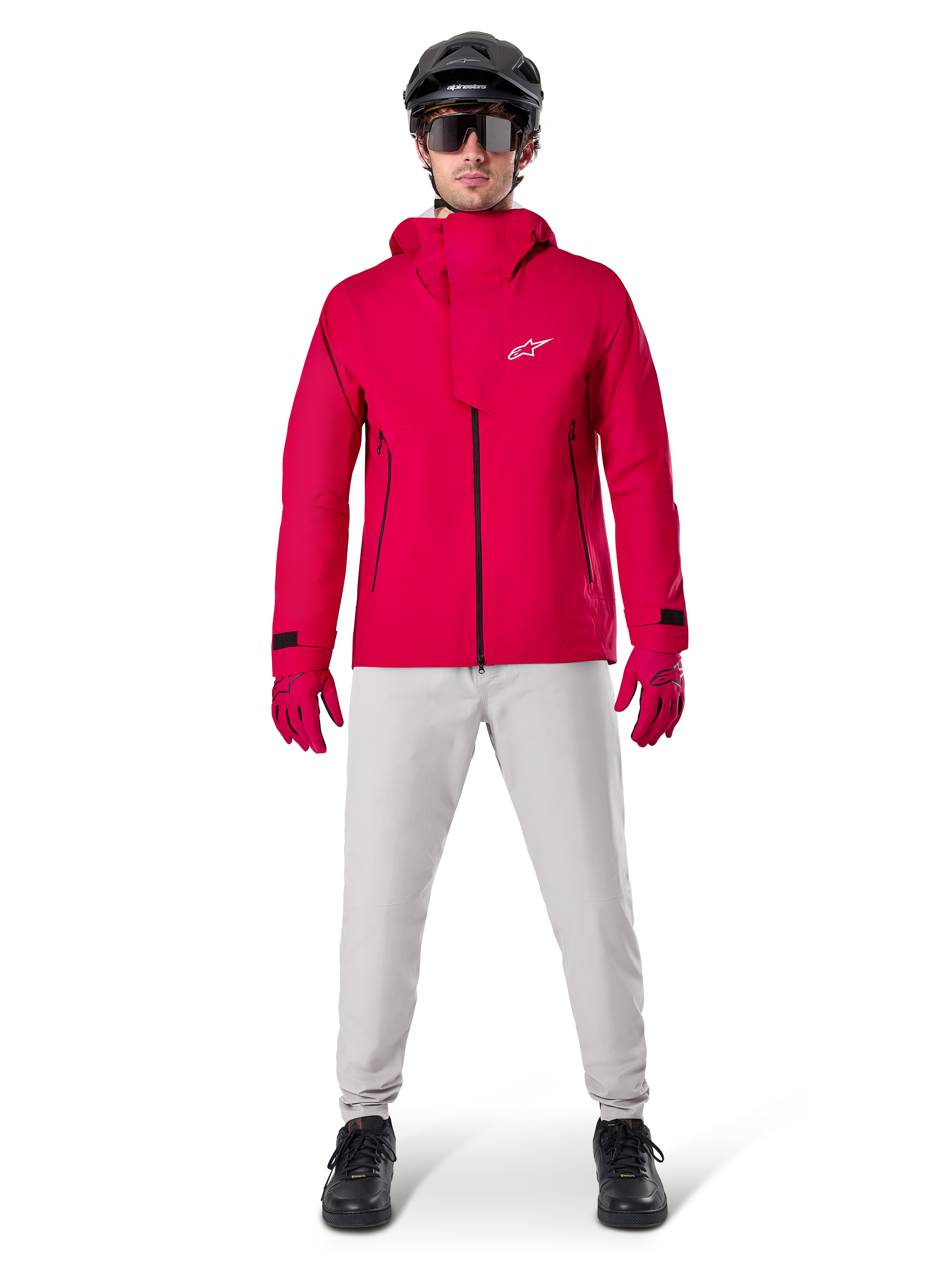 Pantaloni impermeabili Alpinestars A-Dura, pantaloni da MTB, grigio titanio, indossati con una giacca con cappuccio rosso vivace, guanti rossi e un casco da mountain bike nero, abbigliamento tecnico impermeabile professionale per percorsi bagnati