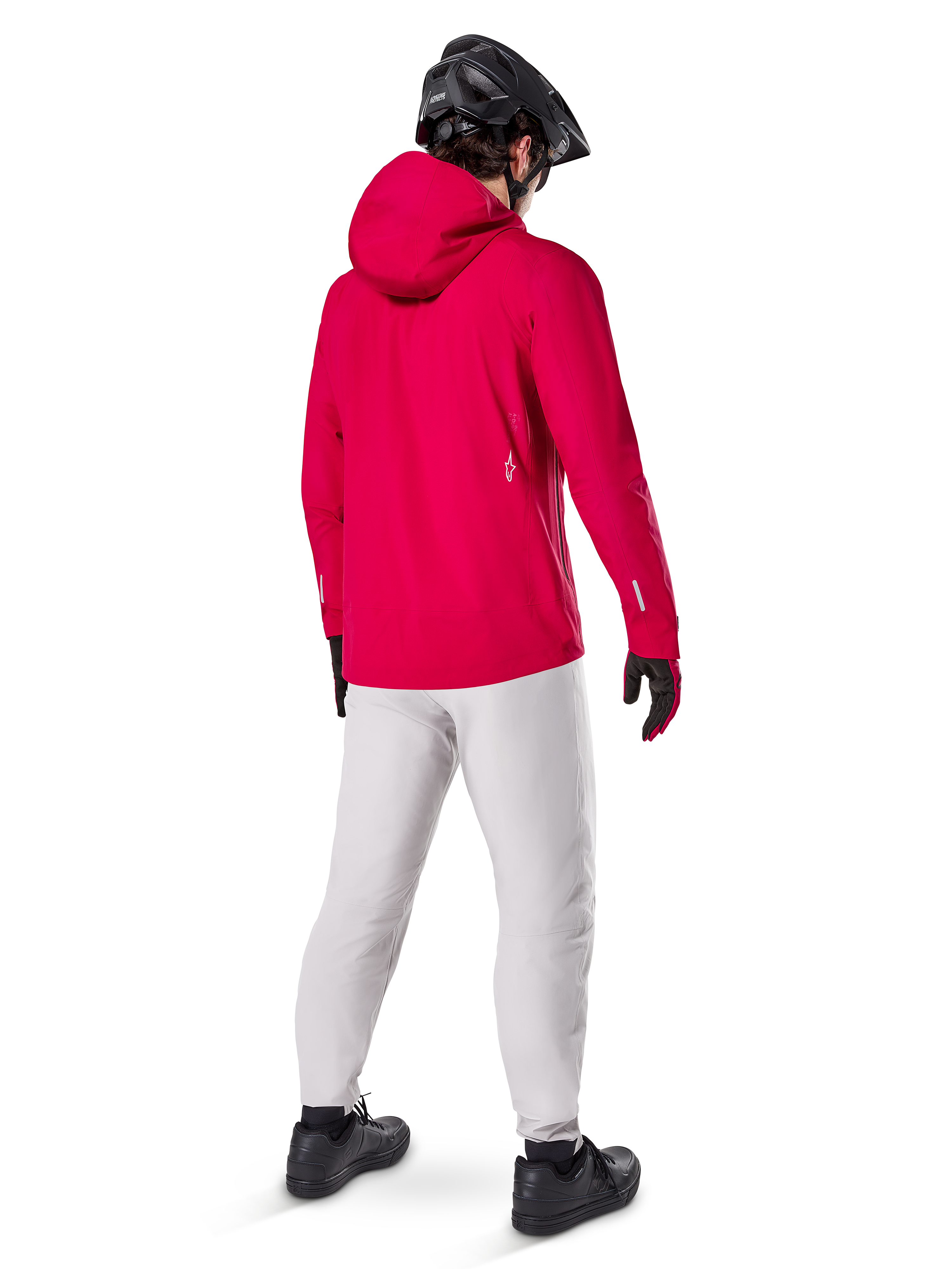 Pantaloni impermeabili Alpinestars A-Dura in Titanium, vista posteriore di un rider che indossa i pantaloni tecnici da mountain bike grigio chiaro con una giacca rossa con cappuccio e casco nero, abbigliamento impermeabile e resistente per il ciclismo in condizioni di bagnato