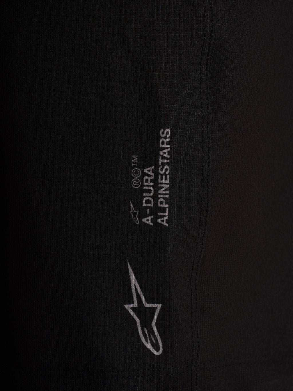 Dettaglio pantaloncini Alpinestars A-Dura Ride neri, tessuto tecnico elasticizzato a 4 vie con loghi bianchi.