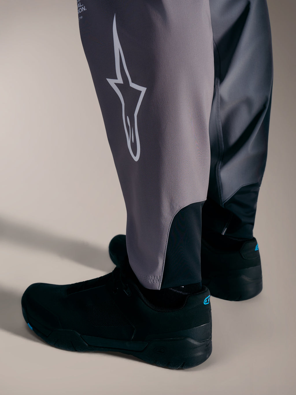 Pantaloni A-Supra Elite grigi con logo Astars bianco e polsini elastici per gare MTB ad alte prestazioni.