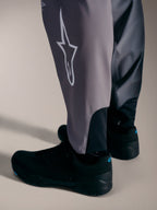 Pantaloni A-Supra Elite grigi con logo Astars bianco e polsini elastici per gare MTB ad alte prestazioni.