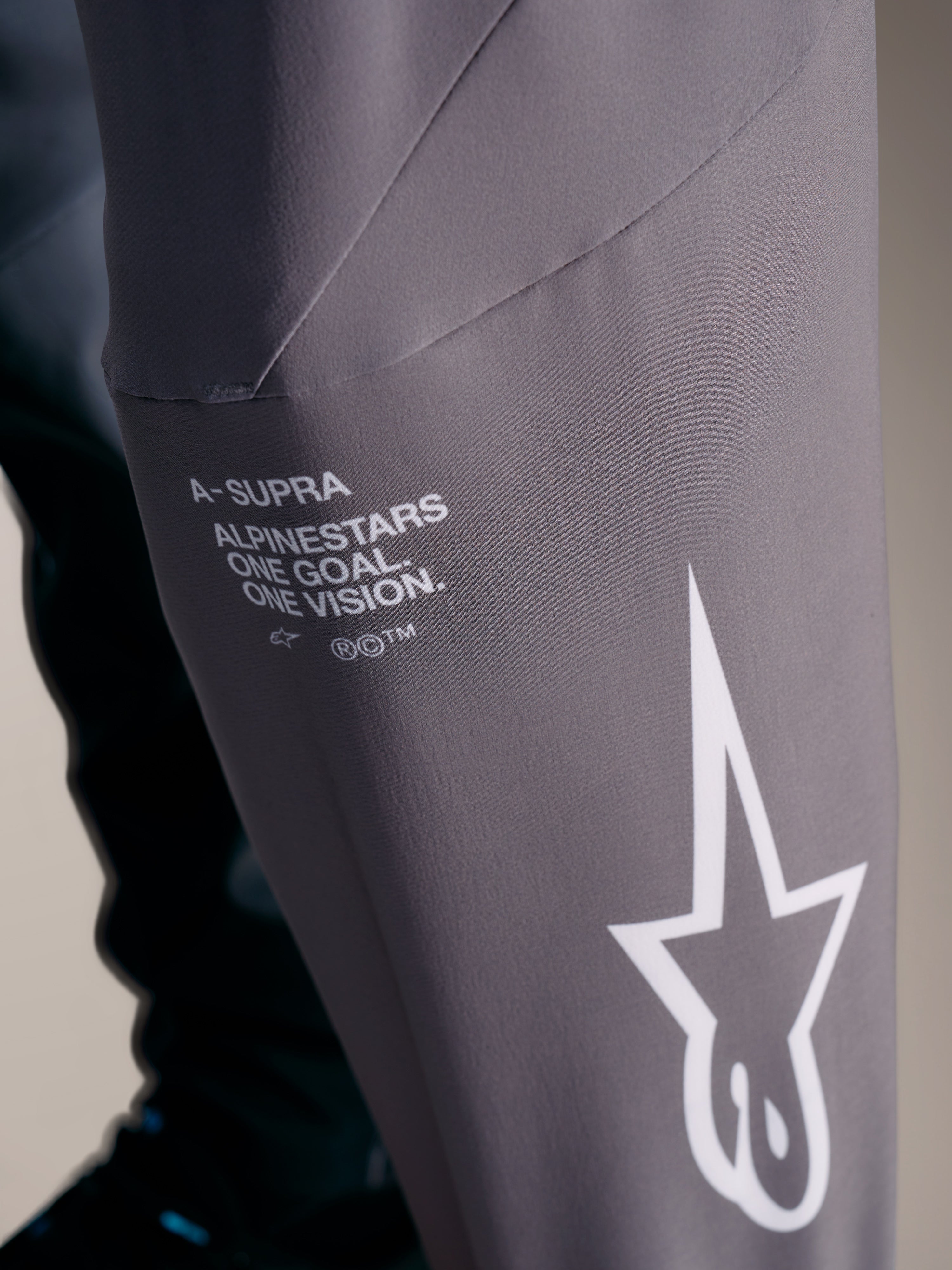 A-Supra Elite Pantaloni grigio sfumato con branding Alpinestars bianco e motto racing 'One Goal. One Vision.'