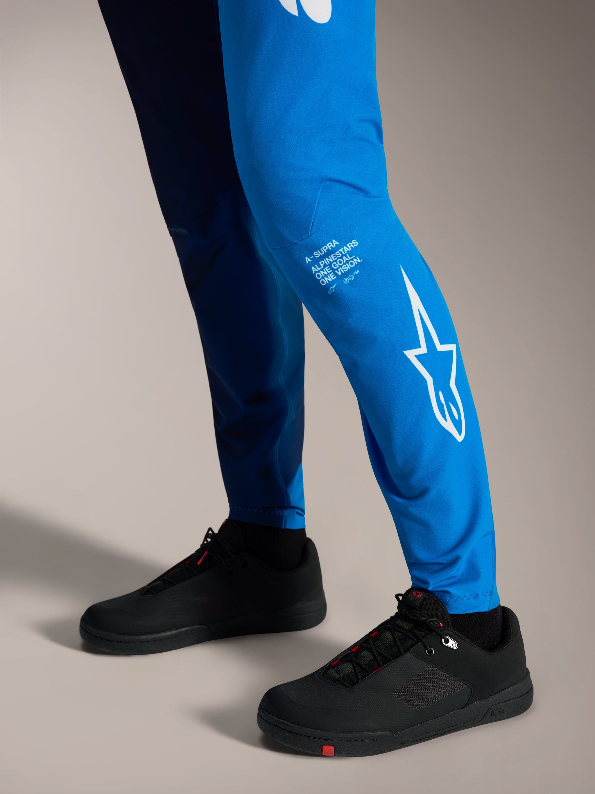 Pantaloni Alpinestars A-Supra Elite in Faded Bright Blue con logo Astars bianco sulla gamba e scarpe da MTB nere.