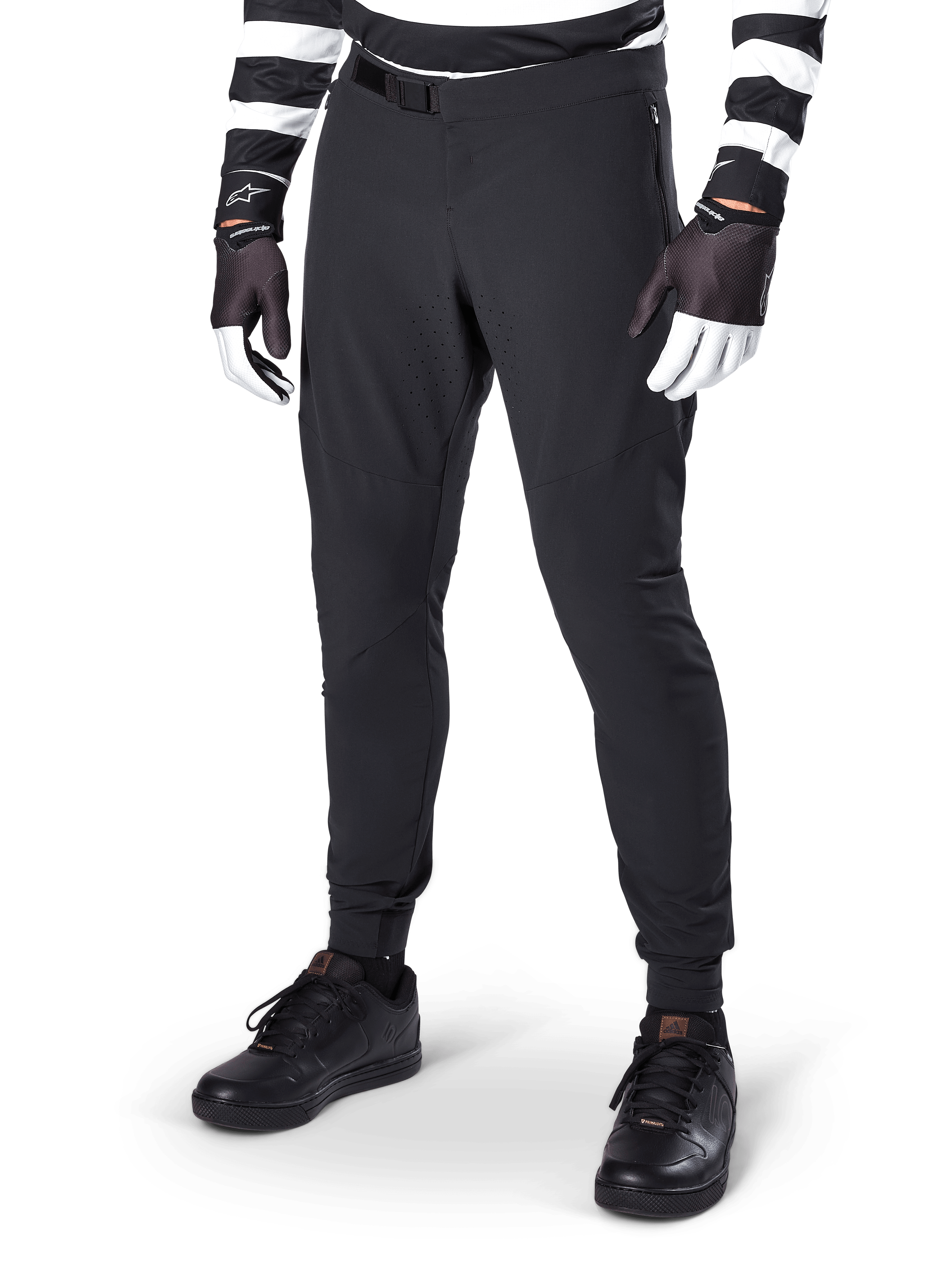 Pantaloni Alpinestars A-Aria Elite, pantaloni neri da mountain bike con ventilazione a taglio laser sulle cosce e chiusura con fibbia magnetica, indossati con maglia a righe bianche e nere e guanti, abbigliamento MTB ad alte prestazioni per il ciclismo fuoristrada