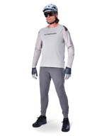 Pantaloni Alpinestars A-Aria Elite, pantaloni MTB grigio scuro, indossati da un rider con maglia a maniche lunghe grigio chiaro e casco grigio, con fori di ventilazione laser sulle cosce e vestibilità tecnica affusolata per mountain bike