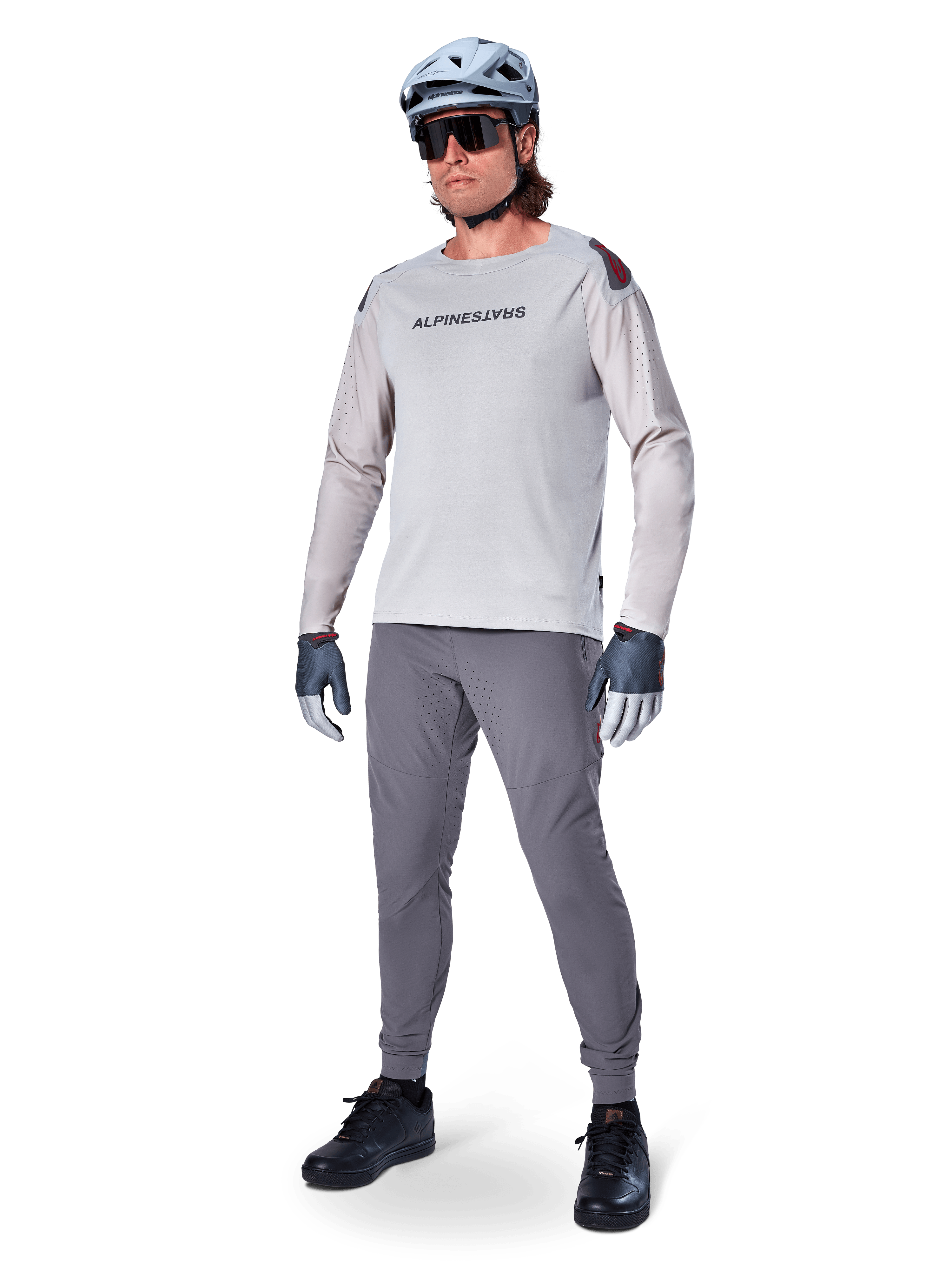 Pantaloni Alpinestars A-Aria Elite, pantaloni MTB grigio scuro, indossati da un rider con maglia a maniche lunghe grigio chiaro e casco grigio, con fori di ventilazione laser sulle cosce e vestibilità tecnica affusolata per mountain bike