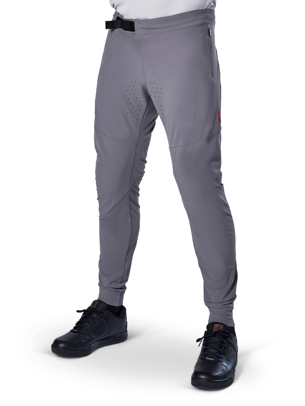 Alpinestars A-Aria Elite Pants, pantaloni da MTB grigio scuro, pannelli traforati al laser sulle cosce, chiusura con fibbia magnetica nera, tasca con zip, dettaglio logo rosso, vestibilità slim performance, indossati con scarpe nere