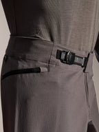 Alpinestars A-Dura Elite Pants, pantaloni MTB, grigio scuro, vista ravvicinata che mostra il sistema di chiusura a cricchetto anteriore e la tasca con zip, abbigliamento tecnico per mountain bike