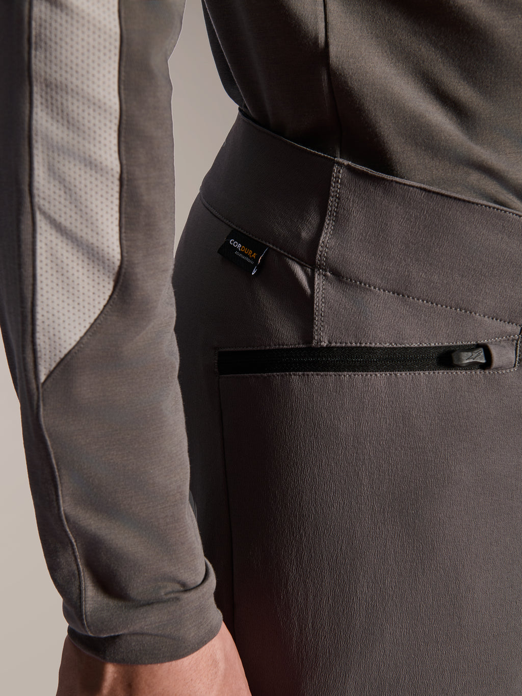 Alpinestars Pantaloni A-Dura Elite, pantaloni da mountain bike grigio scuro, dettaglio ravvicinato della tasca laterale con zip e dell'etichetta in tessuto Cordura, tessuto resistente elasticizzato in 4 direzioni per prestazioni off-road