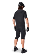 Vista posteriore di un mountain biker che indossa i pantaloncini Alpinestars A-Aria Elite neri, abbinati a una maglia a maniche corte coordinata, casco nero, guanti e scarpe da MTB, che mostra un outfit tecnico completo per il ciclismo off-road.
