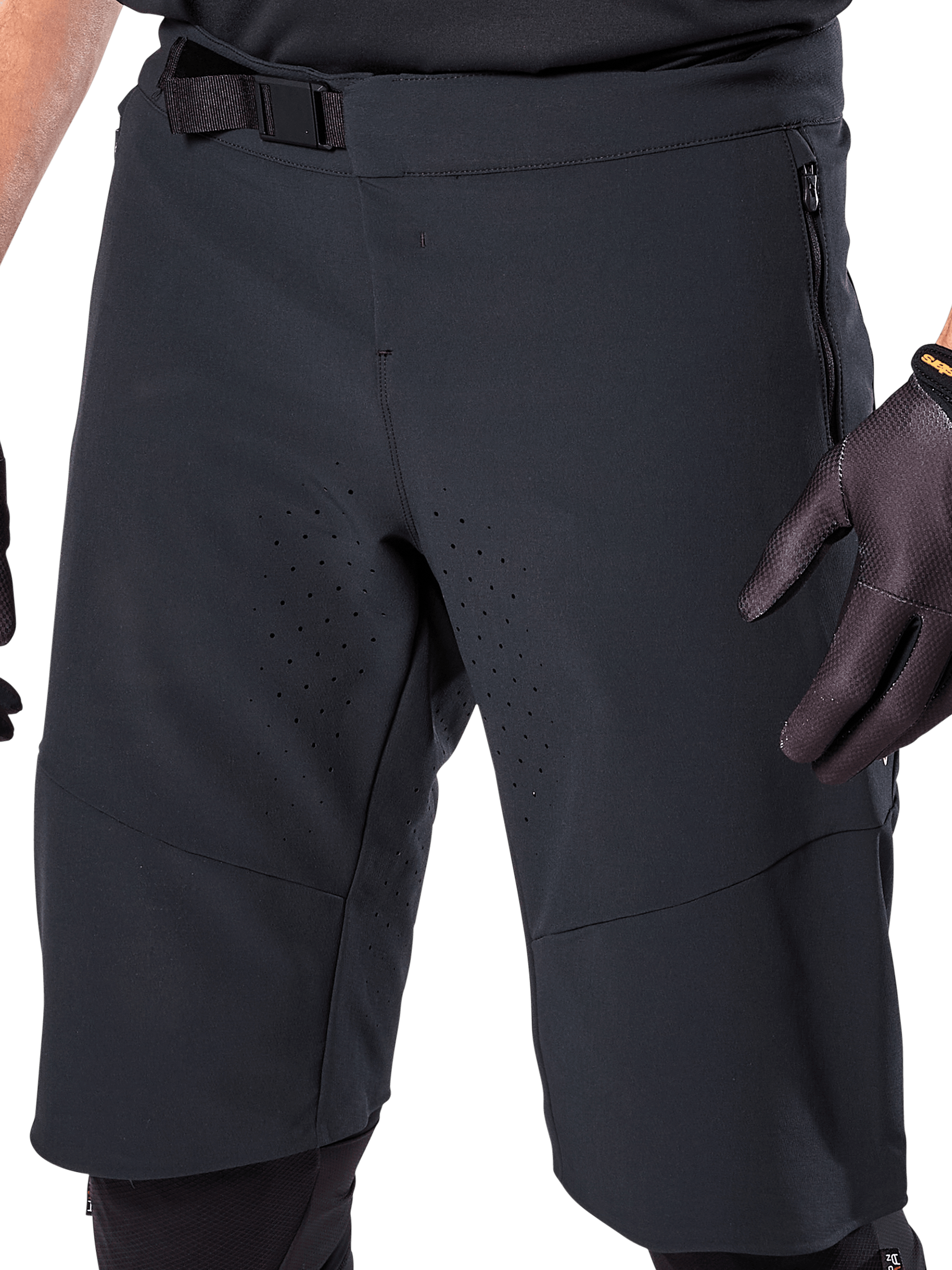 Pantaloncini Alpinestars A-Aria Elite in nero, vista ravvicinata della zona vita e coscia, con chiusura a fibbia magnetica, tasche con zip e perforazioni di ventilazione tagliate al laser, indossati con guanti da ciclismo neri per mountain bike.