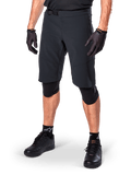 Alpinestars Pantaloncini A-Aria Elite, pantaloncini da ciclismo neri, indossati con guanti e ginocchiere neri coordinati, dotati di fibbia magnetica e perforazioni tagliate al laser, design essenziale per mountain bike fuoristrada