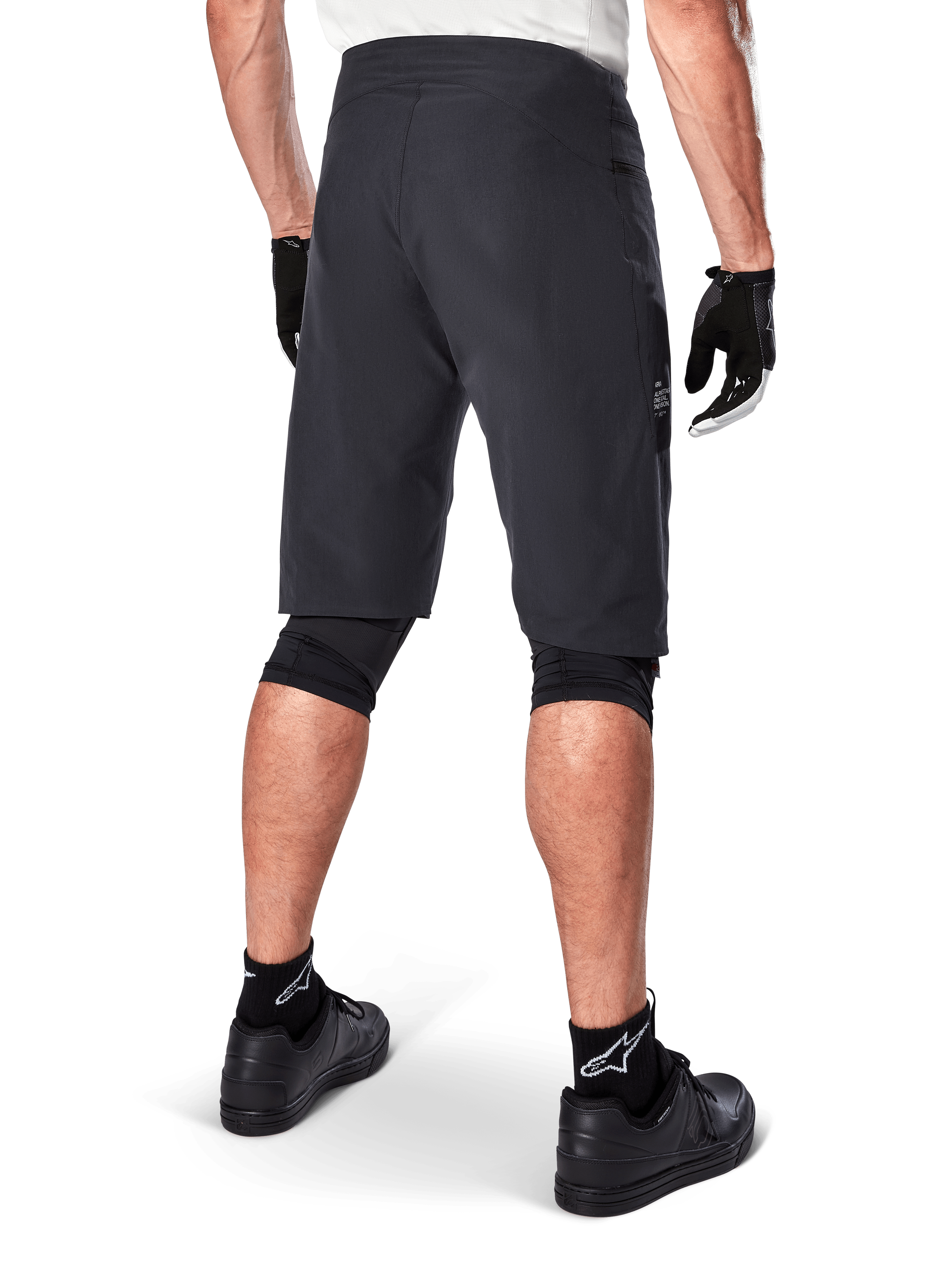Alpinestars Pantaloncini A-Aria, pantaloncini da mountain bike, nero, vista posteriore che mostra la vestibilità performante e il design essenziale, indossati con guanti neri e calze con il logo Astars bianco, abbigliamento tecnico da ciclismo per fuoristrada