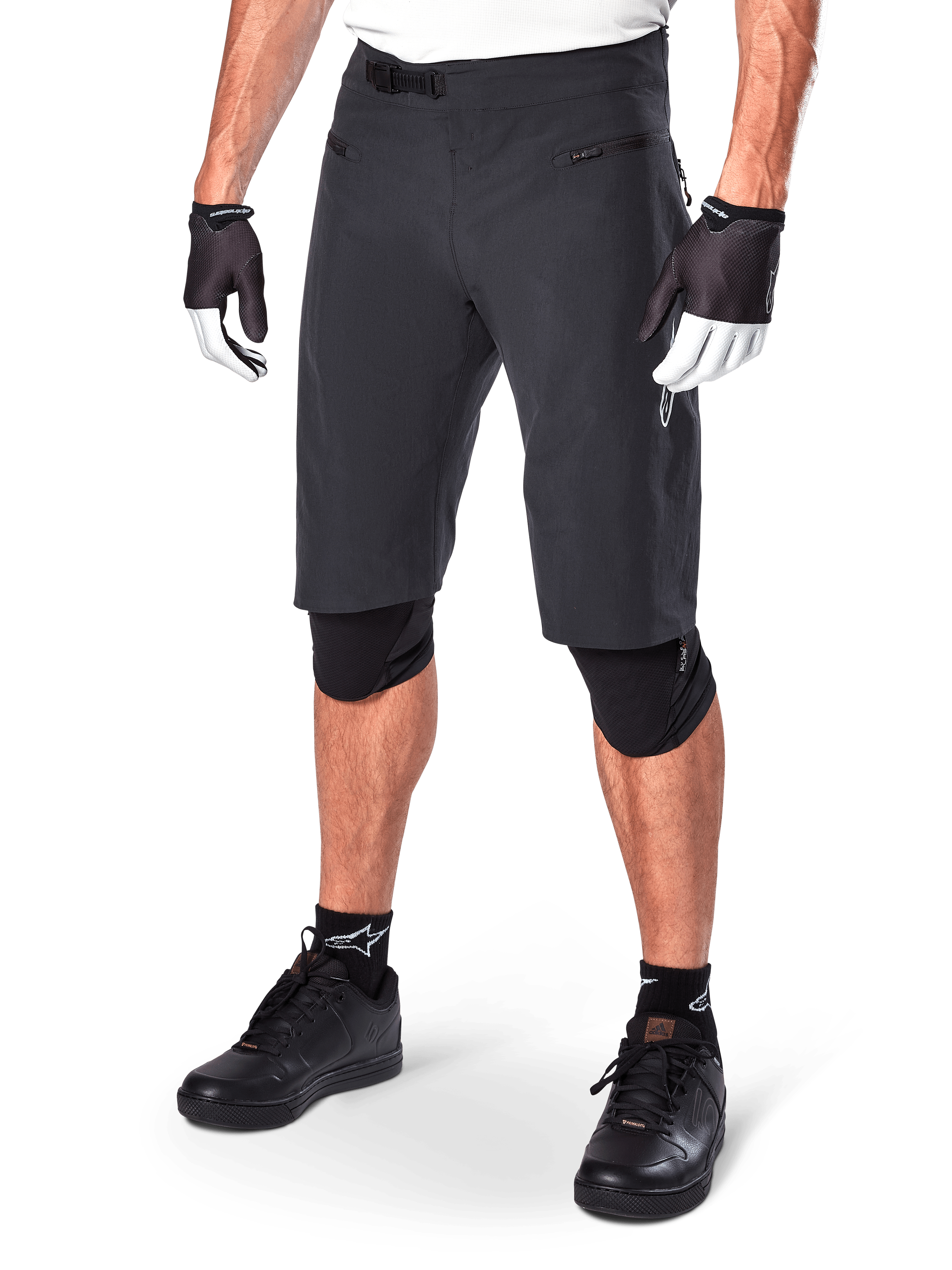 Alpinestars A-Aria Shorts, pantaloncini da mountain bike, neri, lunghezza al ginocchio con tasche anteriori con zip e fibbia a cricchetto regolabile in vita, indossati con ginocchiere nere, calze e guanti da ciclismo