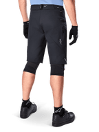 Pantaloncini Alpinestars A-Dura Elite, nero, vista posteriore di un ciclista con abbigliamento da mountain bike, incluse ginocchiere nere, guanti e calze con loghi bianchi, con tasche laterali con zip e accenti riflettenti in resistente tessuto Cordura.