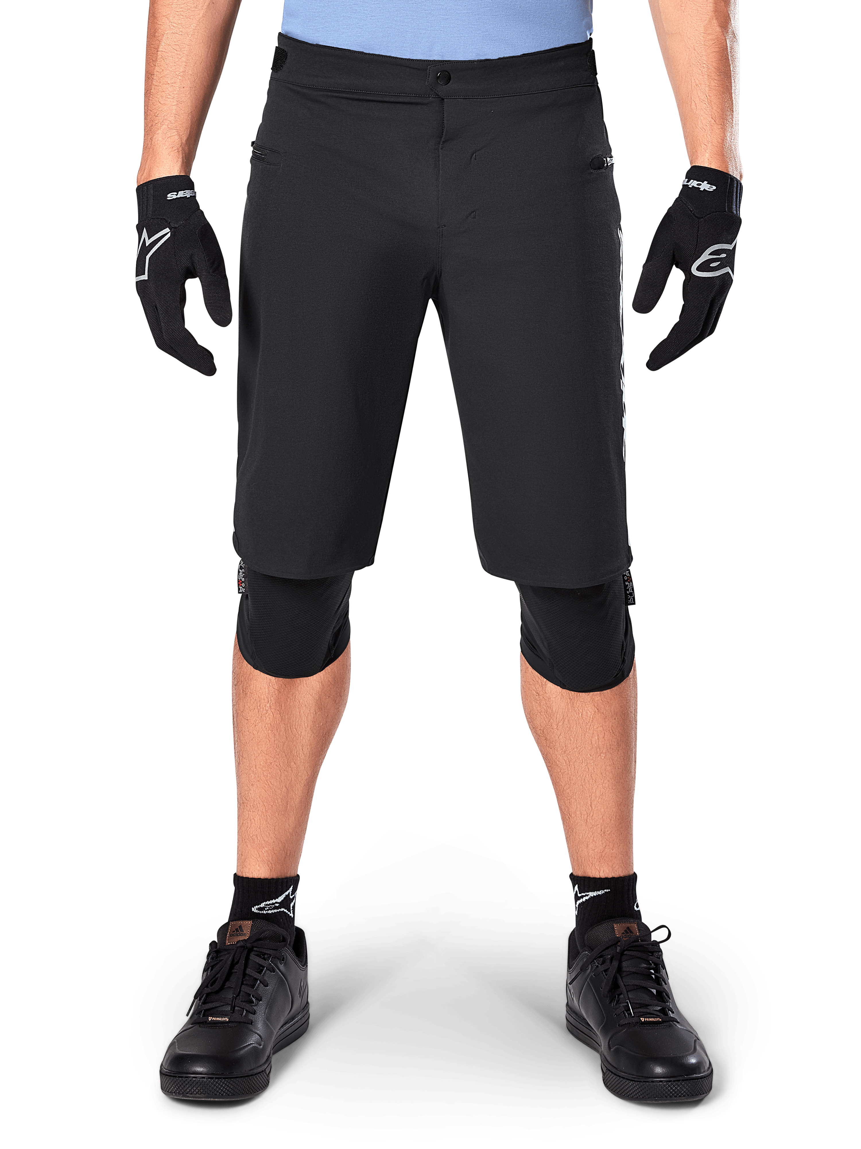 Pantaloncini Alpinestars A-Dura Elite, pantaloncini da mountain bike neri, indossati da un ciclista con guanti e ginocchiere neri, dotati di chiusura frontale a scatto e tasche con zip, in resistente materiale Cordura per il ciclismo fuoristrada